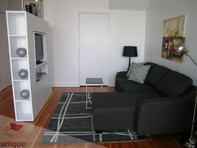 Furnished living room with dark grey sofa, white shelving unit, and modern decor. - 902 - 528 Beatty Street, Vancouver Downtown