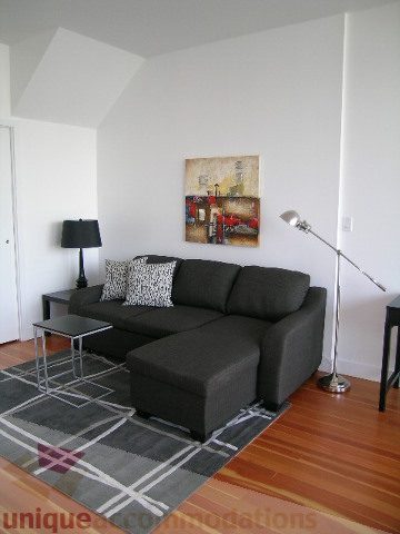 Furnished living room with dark gray sectional, hardwood floors, and abstract art on the wall. - 902 - 528 Beatty Street, Vancouver Downtown