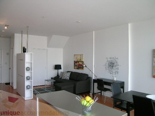Spacious living room with modern decor, hardwood floors, and a sleek kitchen counter. - 902 - 528 Beatty Street, Vancouver Downtown