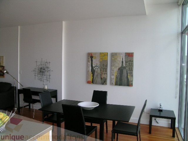 Furnished dining area with black table, chairs, and artwork on white walls; hardwood floors. - 902 - 528 Beatty Street, Vancouver Downtown