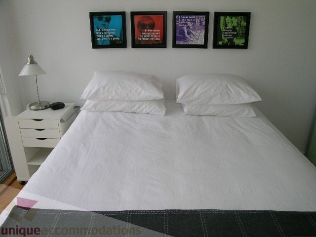 Bright bedroom with white bedding and framed artwork on the wall. - 902 - 528 Beatty Street, Vancouver Downtown
