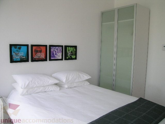 Furnished 1-bedroom with white bedding, modern decor, and a large closet. - 902 - 528 Beatty Street, Vancouver Downtown