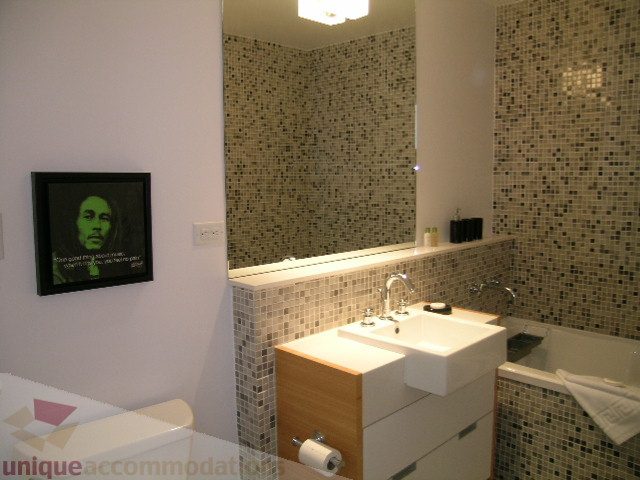 Modern bathroom with mosaic tile walls and a sleek white countertop. - 902 - 528 Beatty Street, Vancouver Downtown