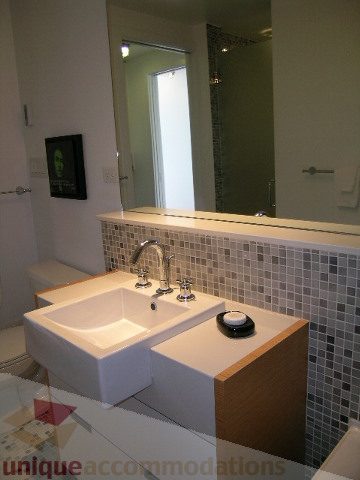 Bright bathroom with modern sink, mosaic tile backsplash, and large mirror. - 902 - 528 Beatty Street, Vancouver Downtown
