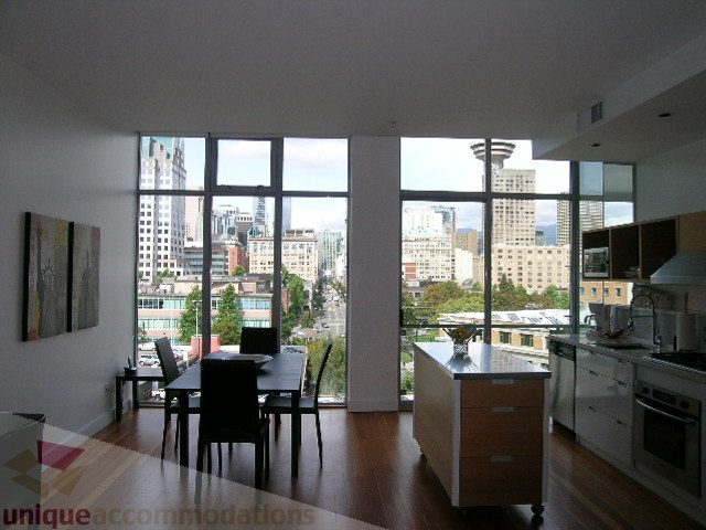 Bright kitchen with hardwood floors and city view, featuring a large island and stainless steel appliances.