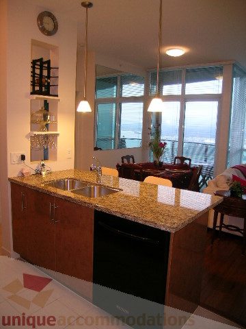 Furnished kitchen with granite countertops and hardwood floors, featuring a city view. - 3802 - 1189 Melville Street, Vancouver Downtown
