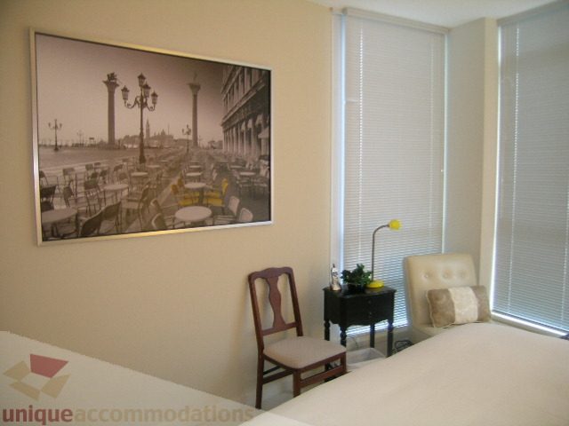 Furnished bedroom with large window, white blinds, and a framed cityscape artwork. - 3802 - 1189 Melville Street, Vancouver Downtown