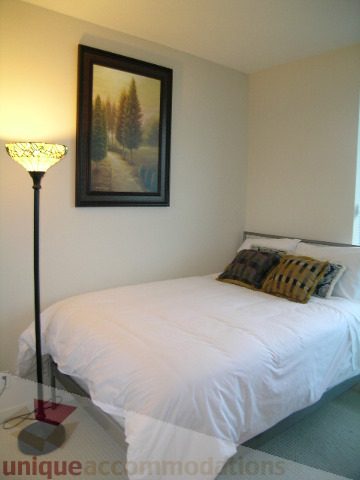 Bright bedroom with two twin beds, white bedding, and a tall floor lamp. - 3802 - 1189 Melville Street, Vancouver Downtown