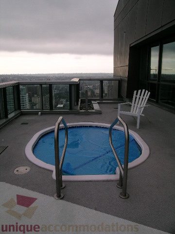 Spacious rooftop patio with a curved hot tub and city view. - 3802 - 1189 Melville Street, Vancouver Downtown