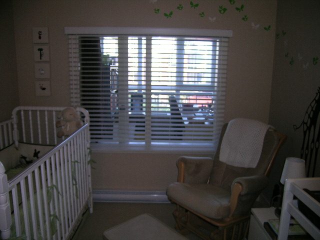 Bright nursery with crib, rocking chair, and butterfly wall decals. - 315 - 4078 Knight Street, Vancouver West Side