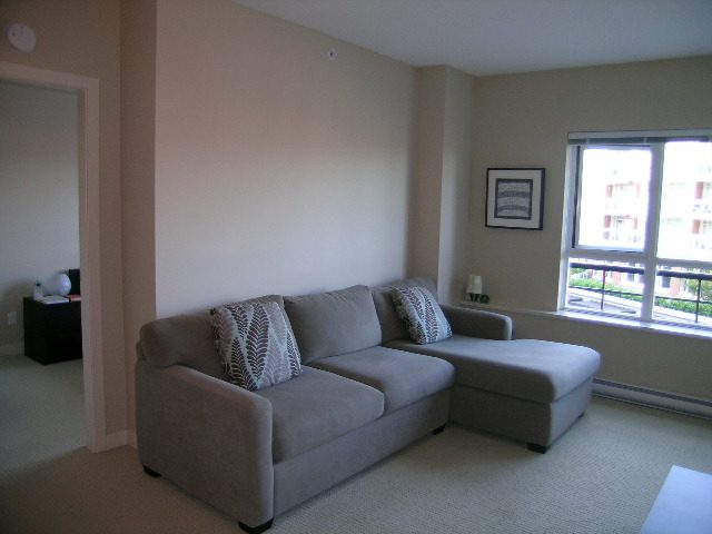 Bright living room with a cozy corner sofa, large windows, and a city view. - 315 - 4078 Knight Street, Vancouver West Side