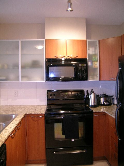 Bright kitchen with granite countertops, black appliances, and wooden cabinets. - 315 - 4078 Knight Street, Vancouver West Side