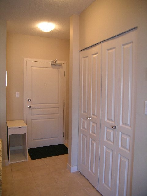 Entryway with white doors and a small bench, clean and minimalistic. - 315 - 4078 Knight Street, Vancouver West Side