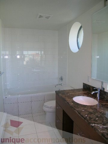 Bathroom with granite countertops, modern sink, and round window. - 2401 - 1005 Beach Avenue, Vancouver Downtown