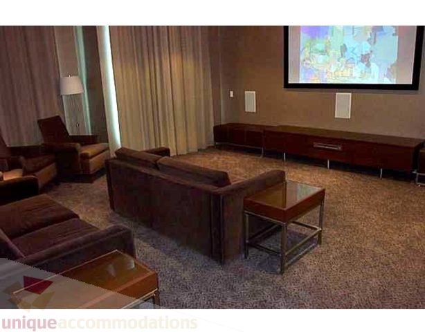 Living room with plush sofas, coffee tables, and a large screen displaying a cartoon. - 2401 - 1005 Beach Avenue, Vancouver Downtown