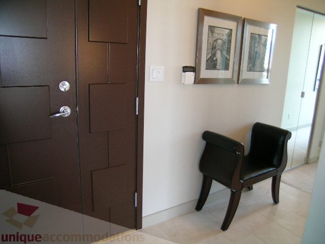 Furnished living room with modern decor, dark wooden door, framed artwork, and sleek furniture. - 4303 - 1408 Strathmore Mews, Vancouver Downtown