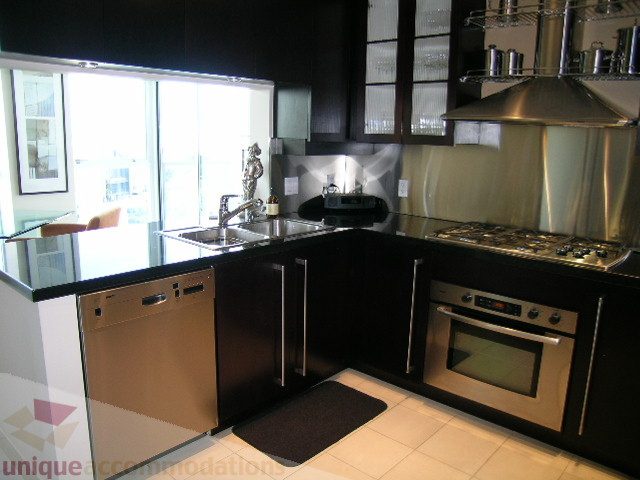 Bright kitchen with black countertops, stainless steel appliances, and a city view. - 4303 - 1408 Strathmore Mews, Vancouver Downtown