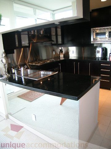 Bright kitchen with sleek black countertops and modern stainless steel appliances. - 4303 - 1408 Strathmore Mews, Vancouver Downtown