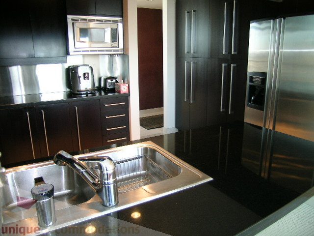 Bright kitchen with stainless steel appliances, black countertops, and modern design. - 4303 - 1408 Strathmore Mews, Vancouver Downtown