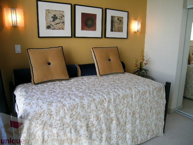 Furnished bedroom with patterned bedding and wall art, warm lighting. - 4303 - 1408 Strathmore Mews, Vancouver Downtown