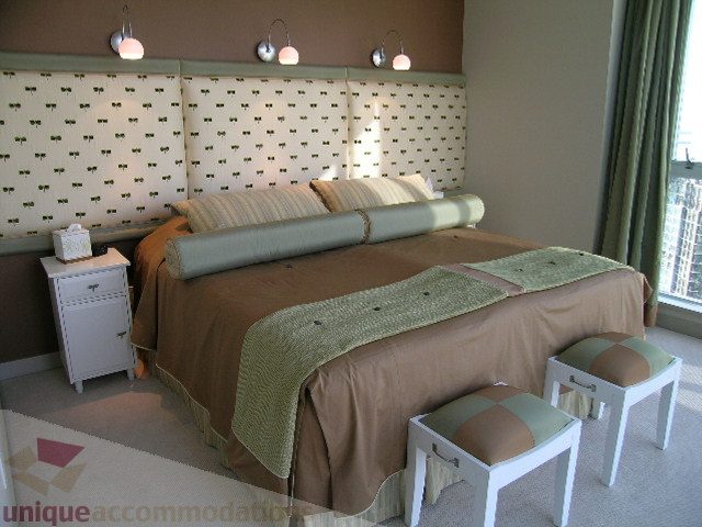 Spacious bedroom with patterned headboard, beige bedding, and a city view. - 4303 - 1408 Strathmore Mews, Vancouver Downtown
