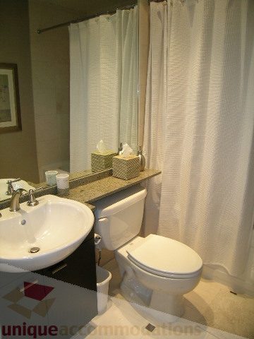 Bathroom with white sink, toilet, and shower curtain. - 4303 - 1408 Strathmore Mews, Vancouver Downtown