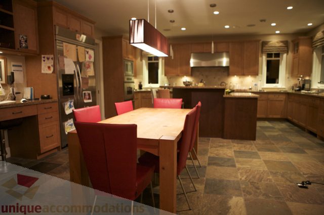 Bright kitchen with wooden cabinets, granite countertops, and red bar stools. - 3781 Bayridge Ave, West Vancouver