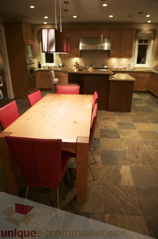 Furnished dining area with wooden table and red chairs, leading to a modern kitchen with stainless steel appliances and...
