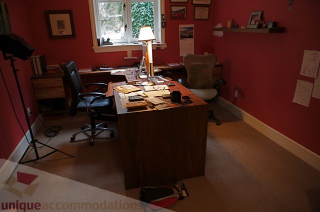 Furnished home office with red walls, wooden desk, and office chair. - 3781 Bayridge Ave, West Vancouver
