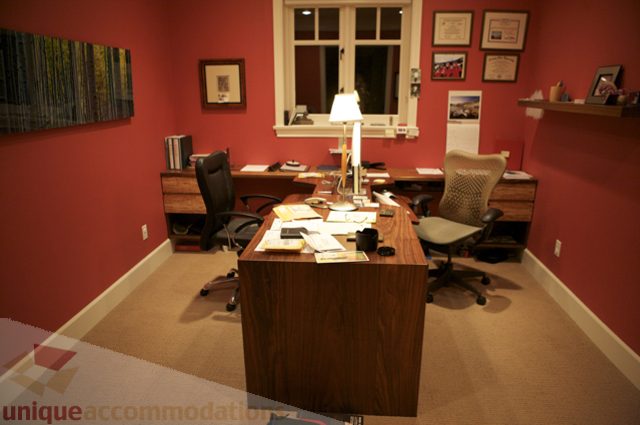 Furnished home office with wooden desk, lamp, and framed artwork. - 3781 Bayridge Ave, West Vancouver