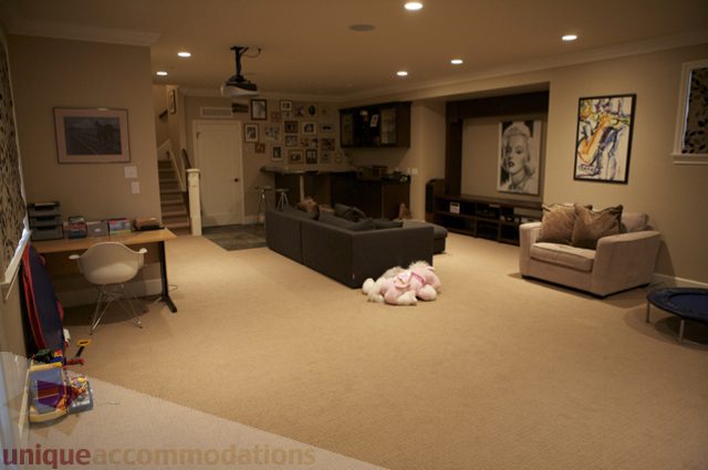 Living room with a sectional sofa, wall-mounted TV, and framed artwork. - 3781 Bayridge Ave, West Vancouver