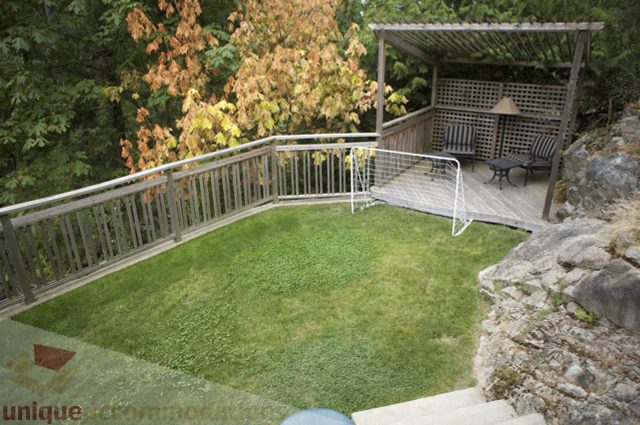Furnished backyard with grass, soccer goal, and wooden deck. - 3781 Bayridge Ave, West Vancouver