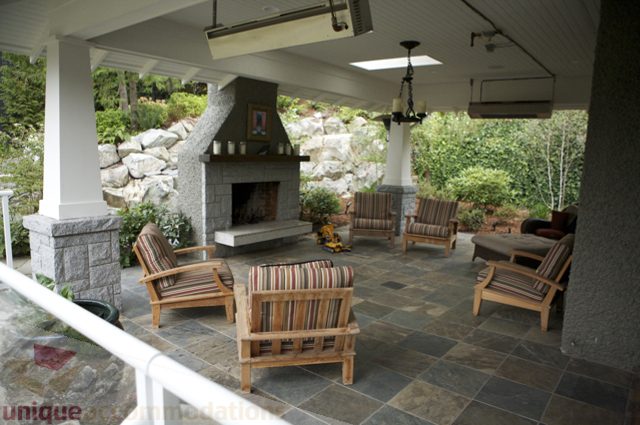 Furnished patio with stone fireplace, outdoor seating, and scenic view. - 3781 Bayridge Ave, West Vancouver