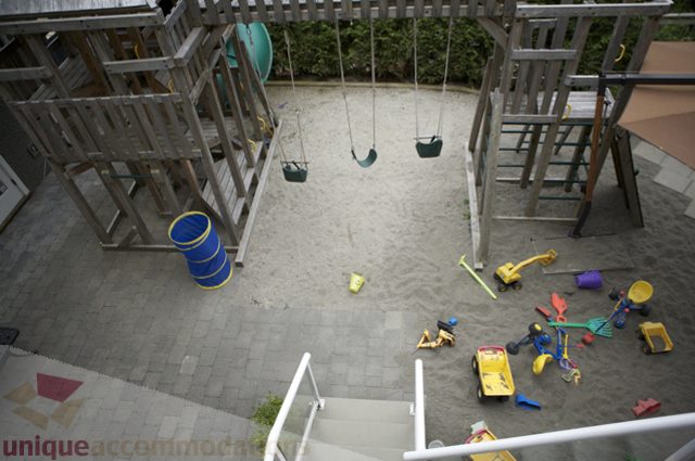 Playful kids' area with swings and sand, toys scattered around. - 3781 Bayridge Ave, West Vancouver
