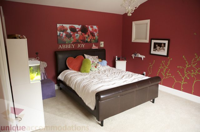 Furnished bedroom with red walls, floral artwork, and modern decor. - 3781 Bayridge Ave, West Vancouver