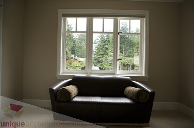 Furnished living room with large windows showing a forest view. - 3781 Bayridge Ave, West Vancouver