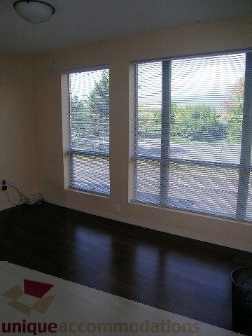 Bright living room with hardwood floors and large windows showing a city view. - 137 Alexander Street, Vancouver Downtown