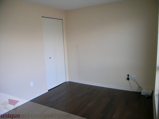Bright living room with hardwood floors and a white door. - 137 Alexander Street, Vancouver Downtown