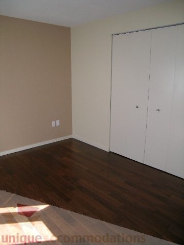 Bright bedroom with hardwood floors and white closet doors. - 137 Alexander Street, Vancouver Downtown