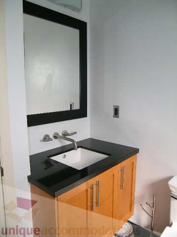 Bathroom with black countertops and wooden cabinets. - 137 Alexander Street, Vancouver Downtown