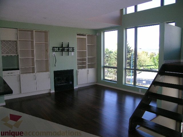 Bright living room with hardwood floors, city view, and built-in shelving. - 137 Alexander Street, Vancouver Downtown