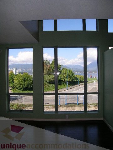 Furnished living room with large windows offering a scenic city view and mountain backdrop. - 137 Alexander Street, Vancouver Downtown