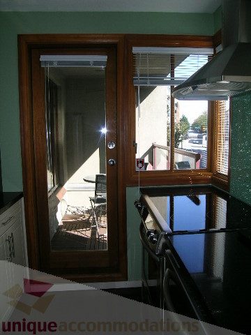 Bright kitchen with green countertops and wooden cabinets, city view through large windows. - 137 Alexander Street, Vancouver Downtown