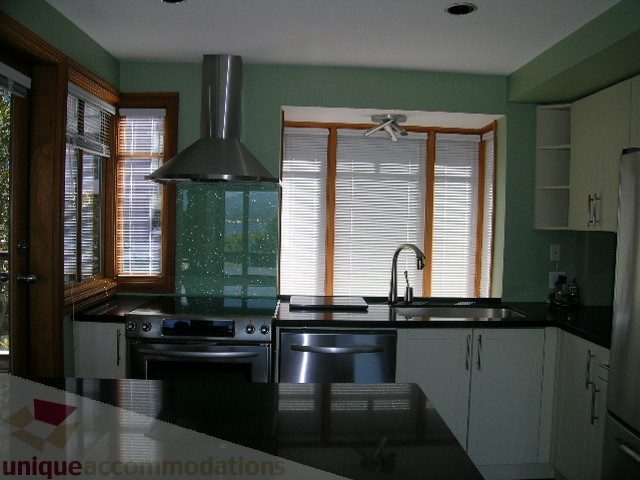 Bright kitchen with modern stainless steel appliances, granite countertops, and a city view through large windows.