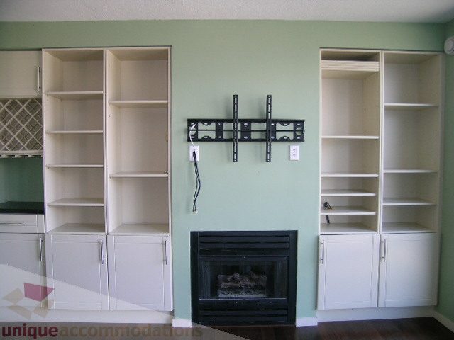 Living room with built-in shelving, fireplace, and wall-mounted TV. - 137 Alexander Street, Vancouver Downtown