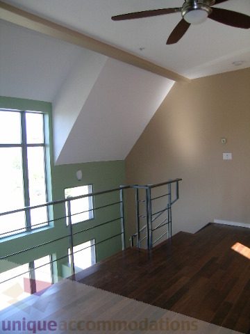 Bright living room with hardwood floors and a ceiling fan, featuring a staircase leading to a den area. - 137 Alexander Street, Vancouver Downtown