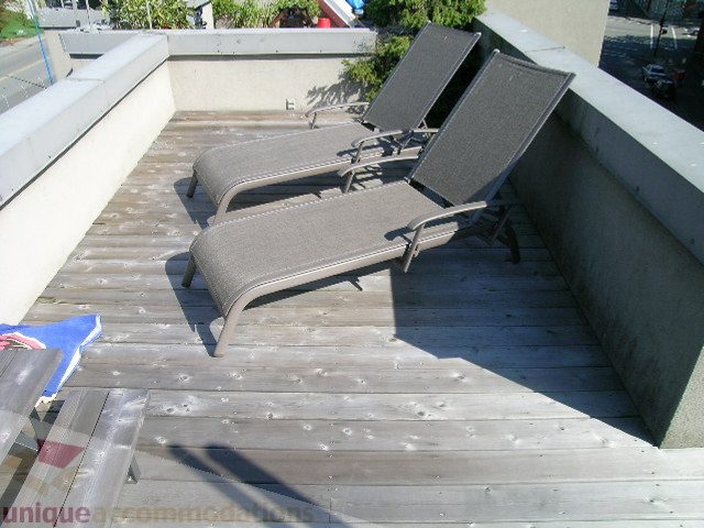 Furnished rooftop deck with lounge chairs and wooden flooring. - 137 Alexander Street, Vancouver Downtown