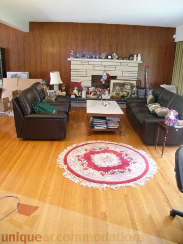 Furnished living room with hardwood floors, a large fireplace, and patterned rugs. - 4408 Arbutus Street, Vancouver West Side