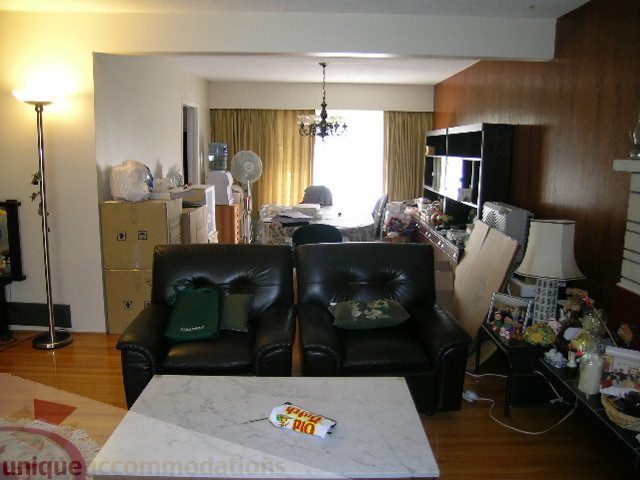 Living room with cluttered furniture and boxes, hardwood floors, and a chandelier. - 4408 Arbutus Street, Vancouver West Side