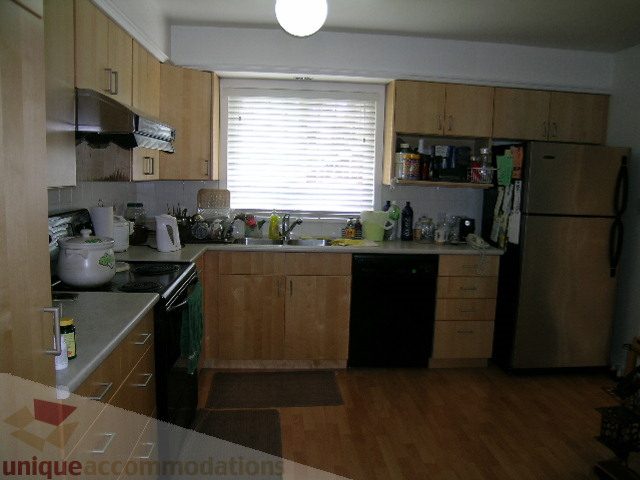 Bright kitchen with wooden cabinets, hardwood floors, and a window with blinds. - 4408 Arbutus Street, Vancouver West Side